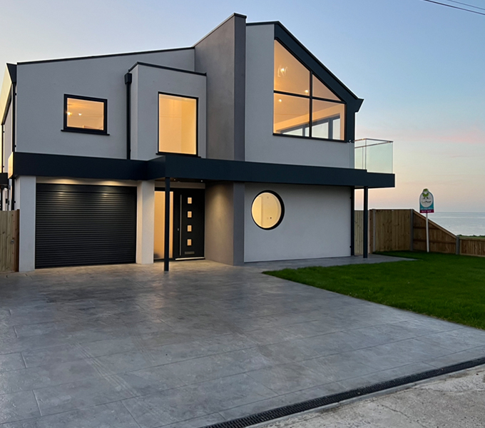 a newly built modern white house with large windows located next to the sea