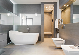 a large grey walled bathroom with a bathtub, toilet sink and mirrors around the walls