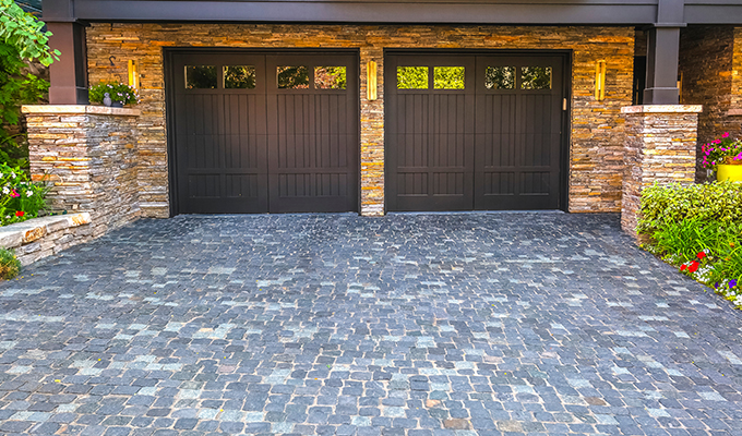 a grey cobble driveway in front of two garages in a building