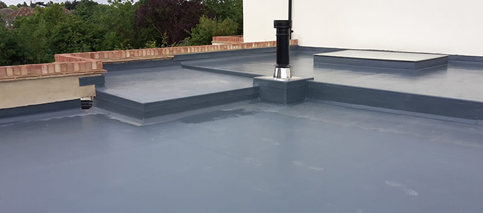 a sleek grey flat roof with a black modern chimney and a skylight