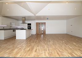 an empty kitchen with an island and a vast laminate floor