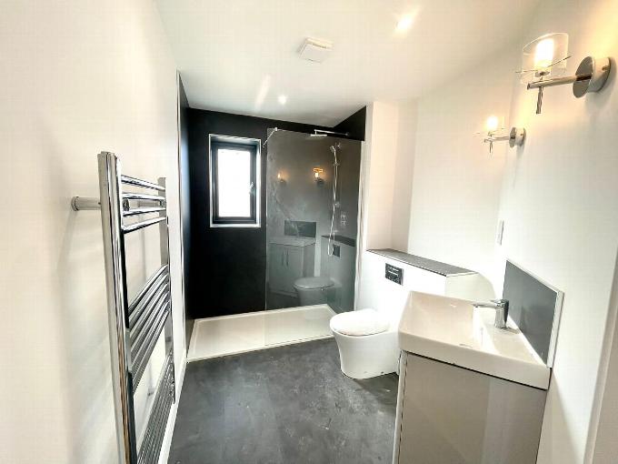a white bathroom with a black shower cubical, toilet and sink